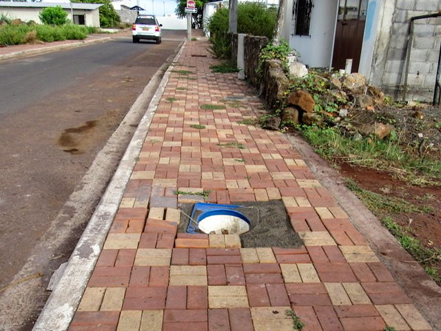 A brick sidewalk with a deep hole in the middle