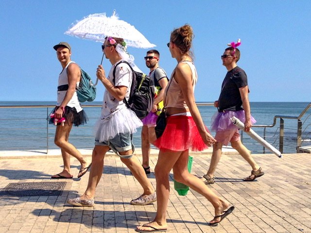 Five people in silly costumes walking on a boardwalk