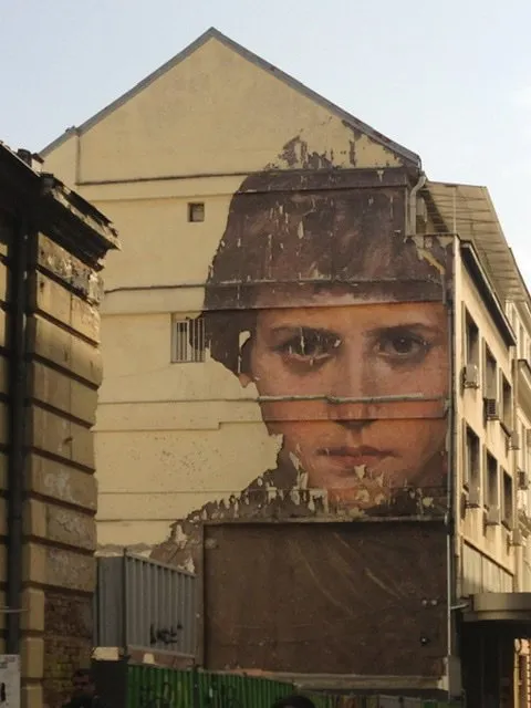 Mural on a serious-looking boy on a yellow building