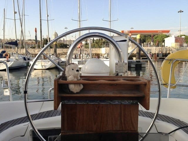 A toy hedgehog sitting at a sailboat’s wheel