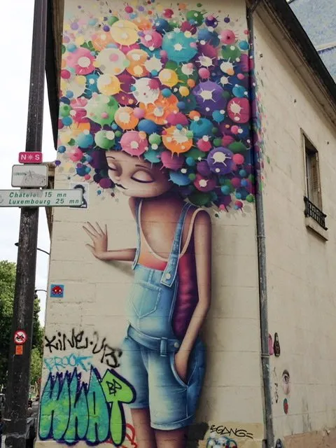 Mural of a girl in overall shorts with colorful balls on her head