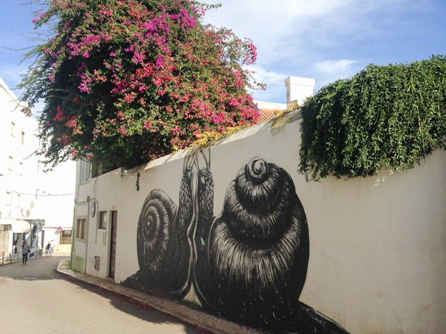 Two black snails facing each other on a large white wall