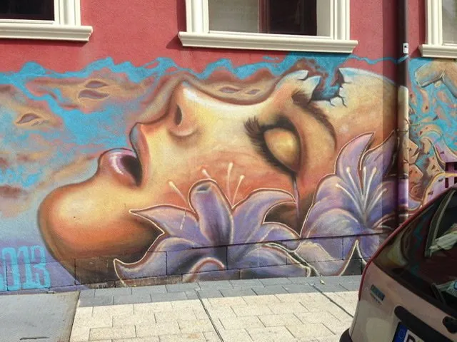 Mural of a woman’s face in profile with light purple flowers