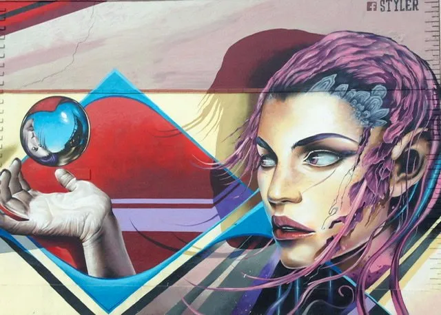 Mural of a woman with purple hair gazing a small crystal ball which is floating above her hand