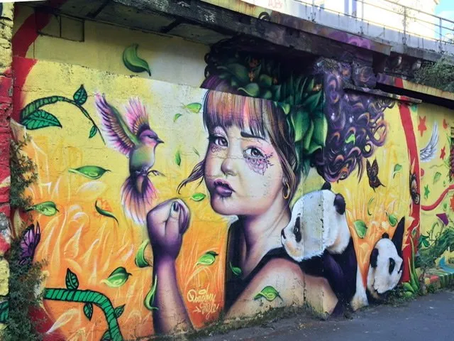 A girl with a panda looking over her shoulder and a bird fluttering in front of her