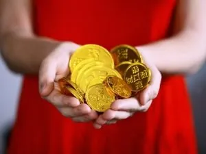 Midsection of a woman in a red dress holding golden coins