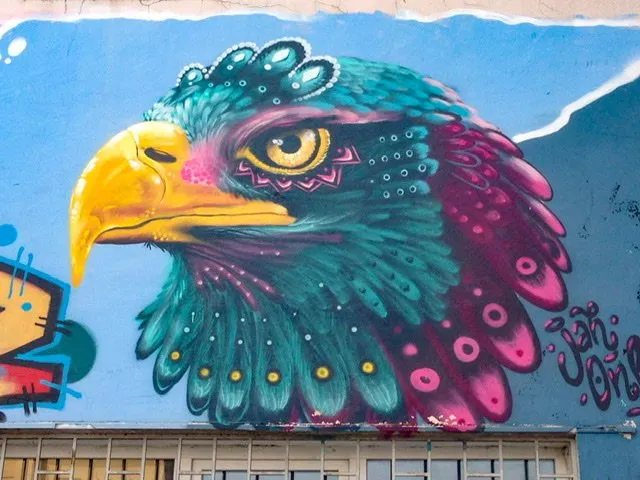 Mural of an eagle in bright yellow, teal, and magenta