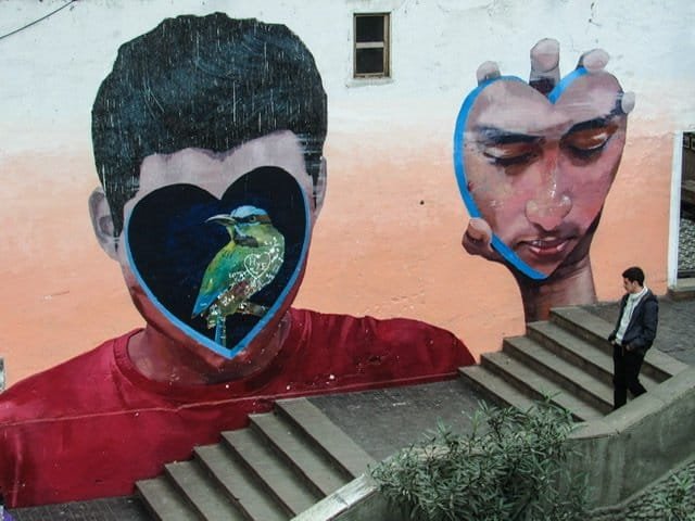 Mural of a boy holding his face next to his head and a bird where his face should be