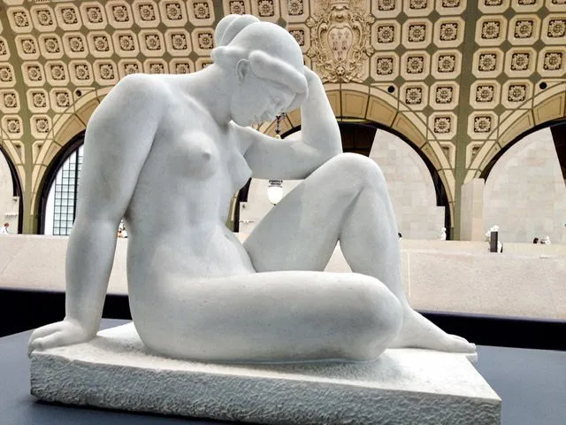 Statue of a nude woman sitting with her head bent forward