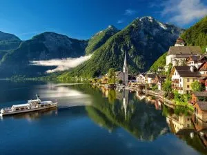 A boat on a mountain lake approaching a quaint village