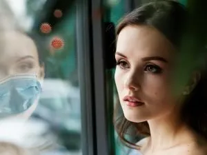 Woman reflected in window with mask and Covid viruses