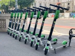 10 electric scooters lined up on a sidewalk