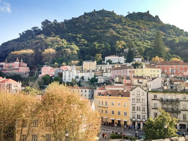 Colorful buildings with tree-covered mountains in the background