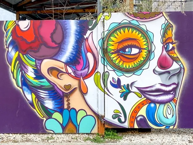 A large mural of a colorfully decorated face