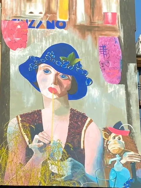 A mural of a woman dring through a straw while sitting next to a monkey