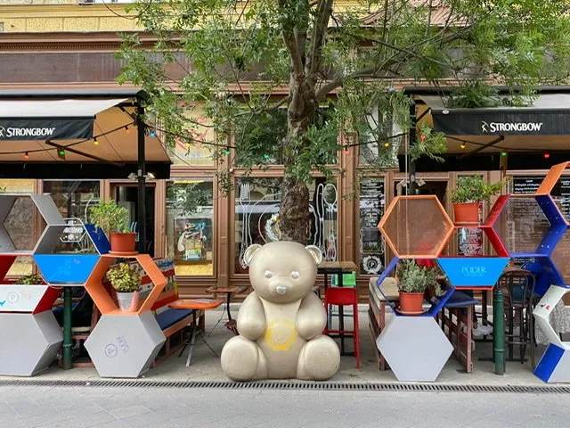 A large gold-tone bear statue sitting on a sidewalk