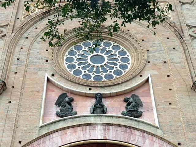 Stained glass window and statues on the front of a cathedral