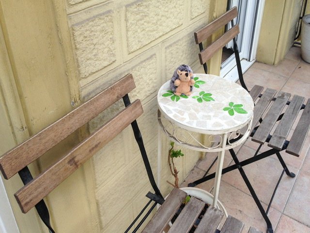 Two chairs and a small table with a stuffed hedgehog on a balcony