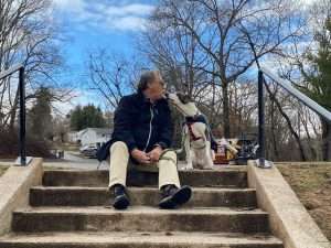 a man sitting on stairs kissing a dog