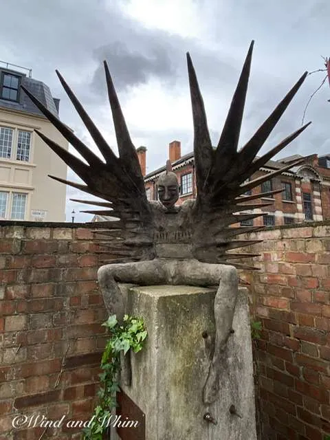 a statue of a man with wings sitting on a pillar