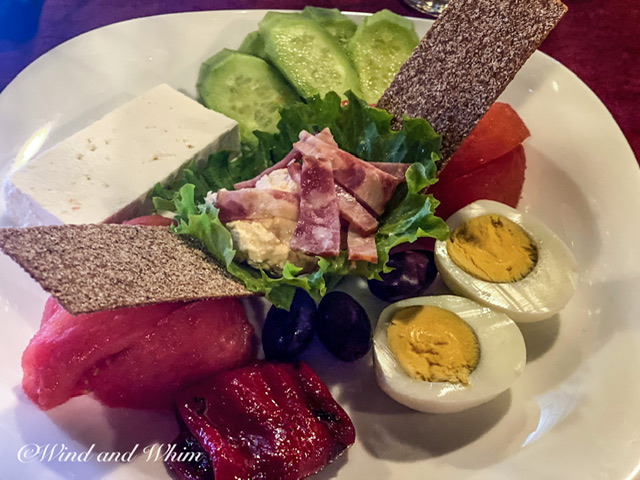 A salad with eggs, olives, ham, cheese, and other food