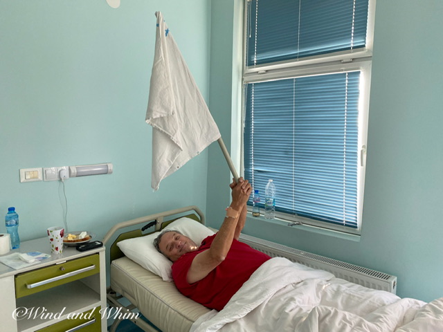 A man lying in a hospital bed waving a white flag