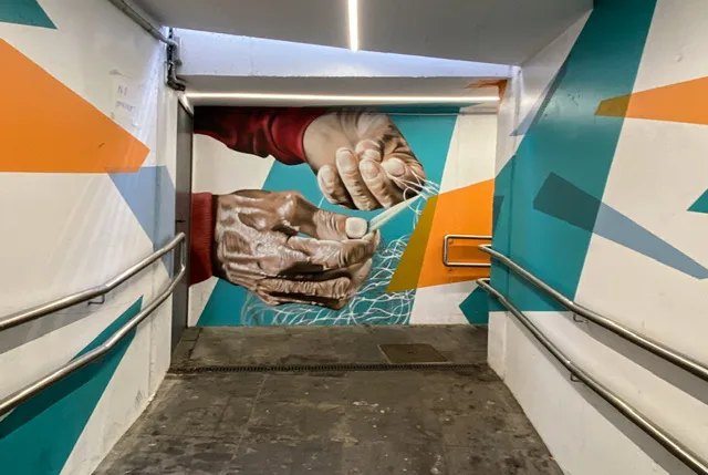 A mural of weathered hands tying a fishing net