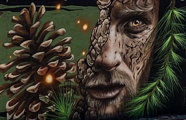 A mural with half a man’s face and a pine cone