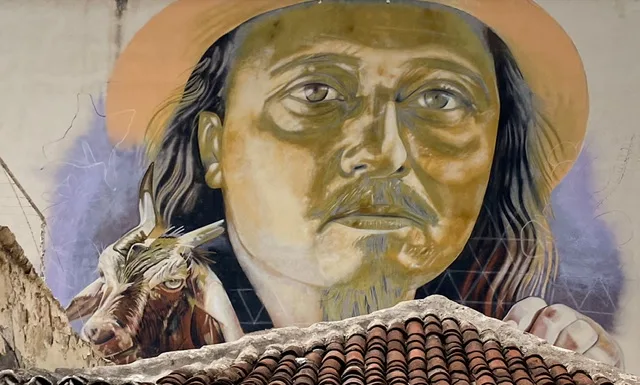 A mural with a Spanish man with a hat and a goat