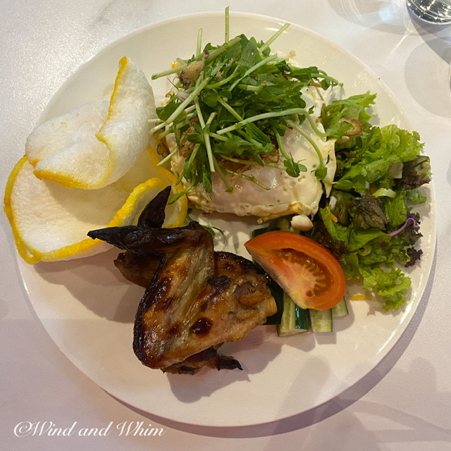 A plate of chicken wings, fried rice with egg, and salad