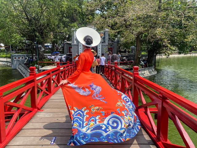 Back view of a woman in traditional Vietnamese dress on a bridge