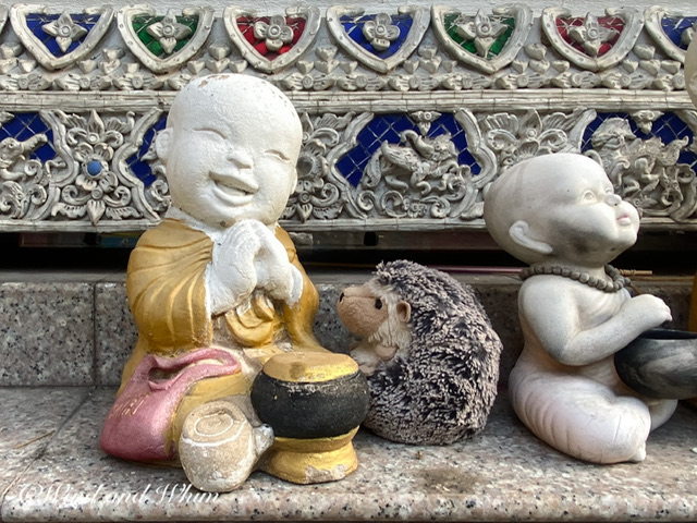 A toy hedgehog and a smiling Buddhist statue