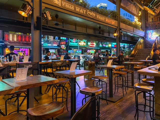 Wooden hi-top tables and stools overlooking stores at night