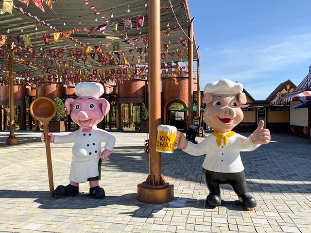 Two pig statues, one holding a mug of beer, the other holding a giant spoon