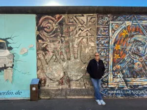 A man standing in front of part of the Berlin Wall