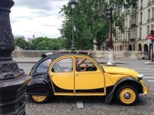 A black and yellow Volkswagen with the dri8ver waving trhough the roof