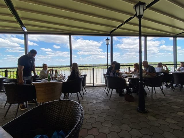 People eating on a patio overlooking a river