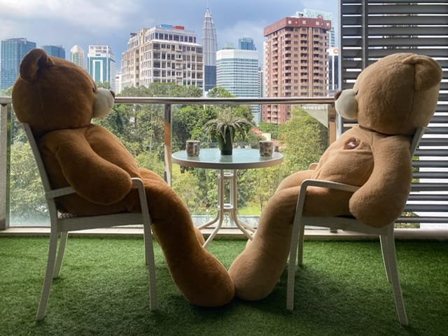 Two human-sized teddy bears sitting on a balcony