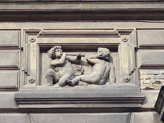 A plaque with one child blowing a horn at another child