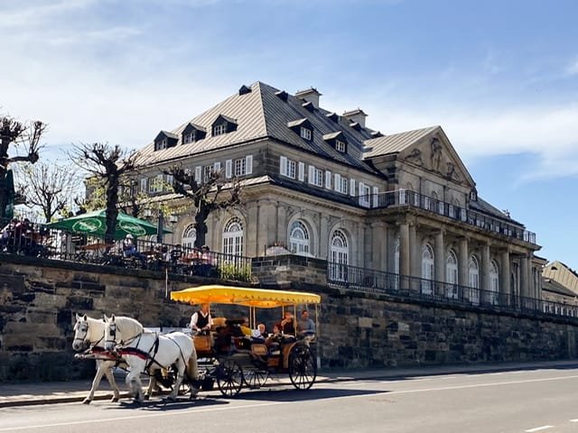 A horse-driven carriage passing a large building