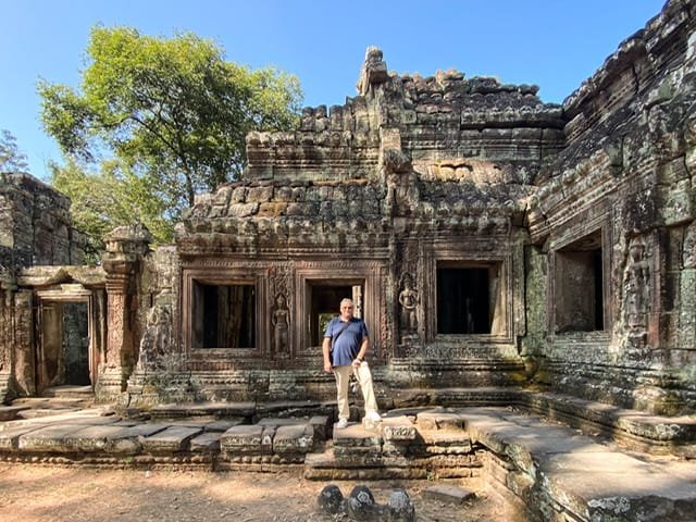 A man standing in front of a large ruin