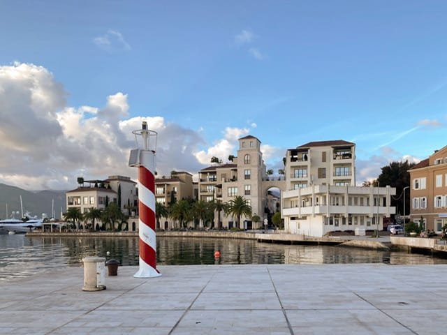 A waterfront promenade with modern buildings and a small lighthouse
