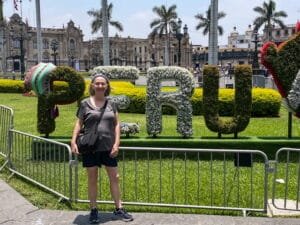 A woman standing in front of a sign reading “PERU”
