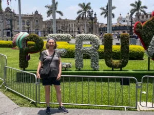 A woman standing in front of a sign reading “PERU”