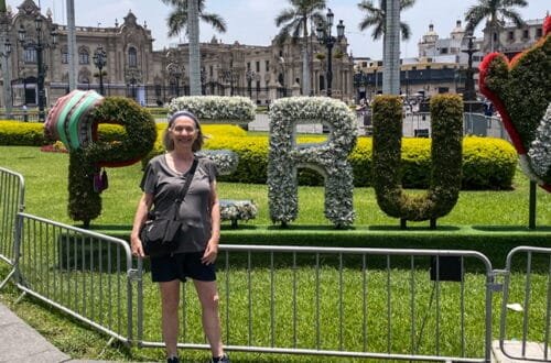 A woman standing in front of a sign reading “PERU”