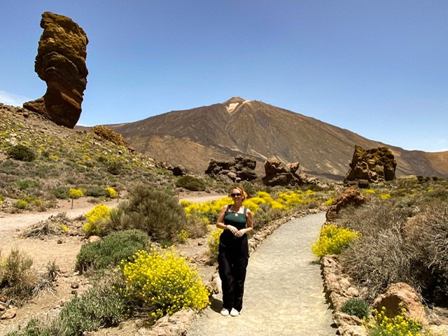 A woman on a path with a volcano in the background