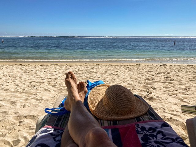 Legs, feet, and a hat on the beach