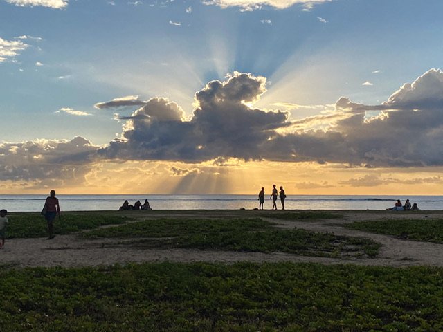 People on the shore as the sun sets