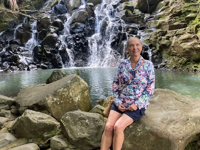 A woman sitting in front of a waterfall