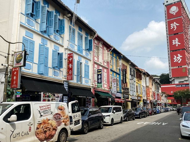 A street with parked vehicles and stores with Chinese signs